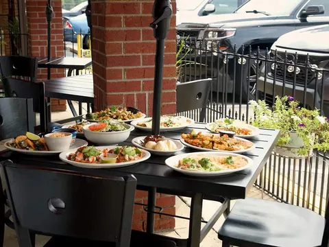 Patio table set with several entrees at Somos Familia