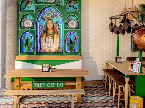 Taco Chelo dining room with a hand-painted Virgen mural, wooden benches, and patterned tile floor