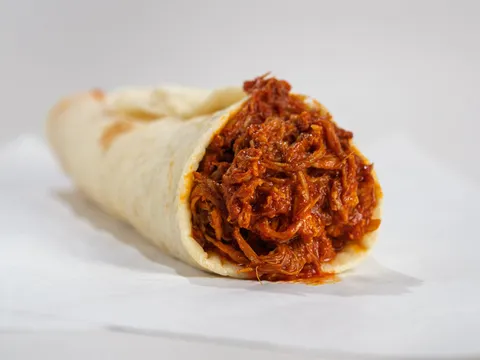 A carne adovada burrito filled with red chile shredded pork in a flour tortilla on paper at Golden Pride in Albuquerque